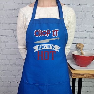 Pu&ograve; includere: Grembiule da cucina blu con un'immagine di coltello bianco e il testo "Chop It Like It's Hot" in rosso.