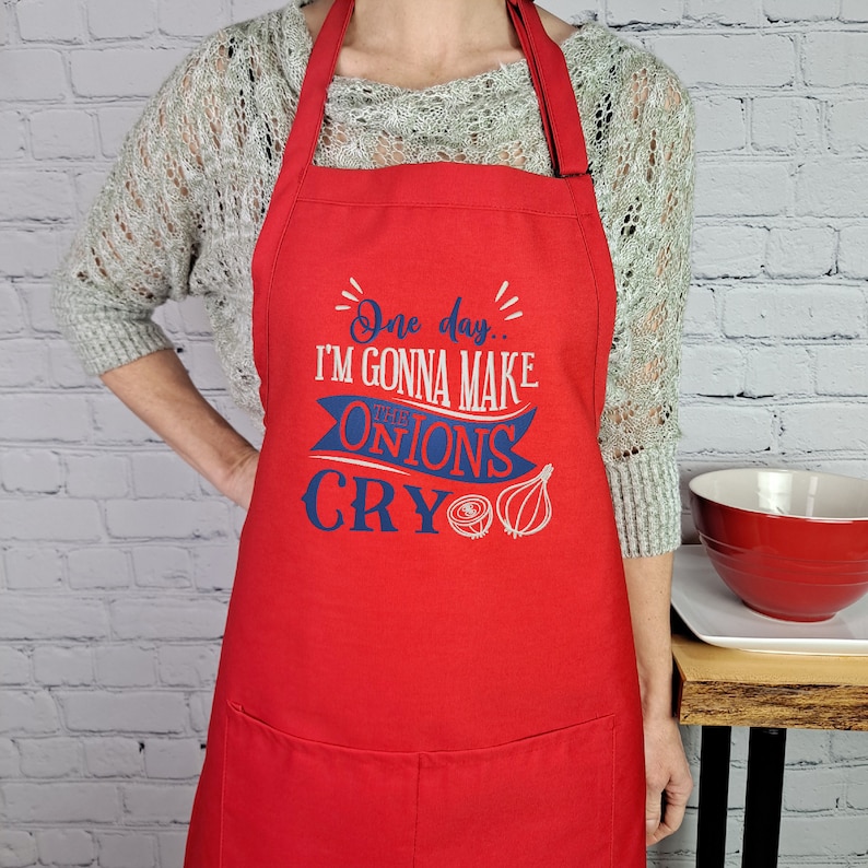 May include: Red kitchen apron with a blue and white graphic that says "One day... I'm gonna make the onions cry".