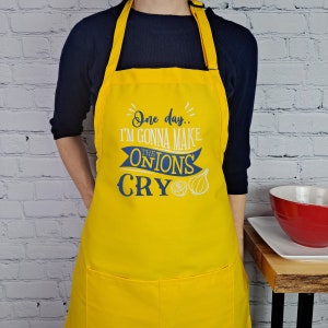 May include: Yellow kitchen apron with a blue and white design that says "One day... I'm gonna make the onions cry".