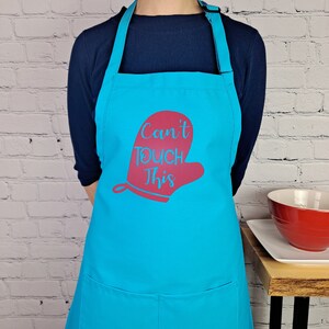 May include: A turquoise blue apron with a red oven mitt graphic and the text "Can't Touch This".