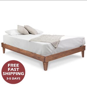 May include: A wooden bed frame with a white mattress and pillows. The bed frame has a light brown finish and four legs.