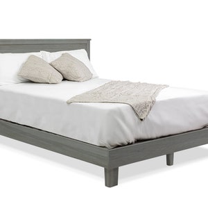 May include: A gray wooden platform bed frame with a white mattress, two pillows, and a white throw blanket.