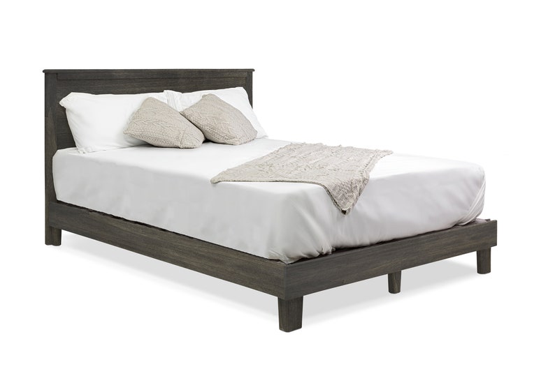 May include: A gray wooden platform bed frame with a white mattress, white pillows, and a white throw blanket.