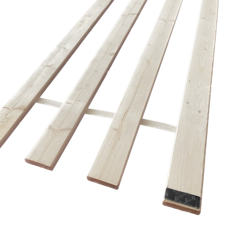 May include: Four wooden planks stacked on top of each other. The planks are light brown and have a smooth surface. The planks are tied together with white straps.