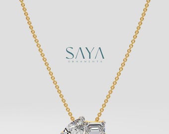 May include: A gold chain necklace featuring a pear-shaped diamond and a rectangular emerald-cut diamond pendant. The pendant is set in a simple, modern style. The necklace is a delicate piece of jewellery that would make a beautiful gift.
