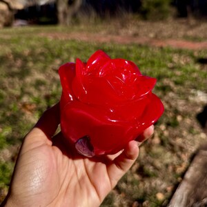 May include: A bright red rose-shaped resin sculpture. The sculpture is detailed with realistic rose petals and a glossy finish.