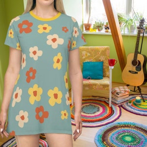 May include: A light blue t-shirt with a floral pattern featuring orange, yellow, and white flowers. The shirt has a crew neck and short sleeves.