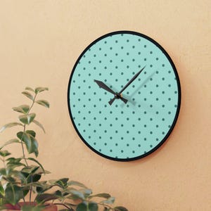 May include: A teal blue round clock with black hands and a white polka dot pattern.