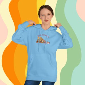 May include: A light blue hoodie with a front pocket and a drawstring hood. The hoodie features a graphic of a sneaker with the words "OLD SCHOOL" above it. The sneaker graphic is in shades of brown, red, and yellow.