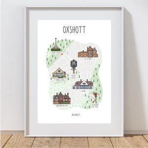May include: A framed print of an illustrated map of Oxshott, Surrey, showing key locations such as Oxshott Heath, St Andrew's Church, and The Victoria. The map is set on a white background, with the town's name in bold black letters at the top.
