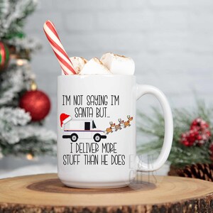 May include: White ceramic mug with a black and white illustration of a mail truck with a Santa hat and reindeer pulling it. The text on the mug reads "I'm not saying I'm Santa but... I deliver more stuff than he does."