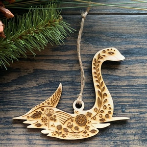 Puede incluir: Un adorno de madera en forma de cisne con un dise&ntilde;o floral, perfecto para colgar en un &aacute;rbol de Navidad o a&ntilde;adir un toque de naturaleza a la decoraci&oacute;n de tu hogar.