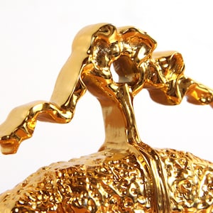 May include: A gold-colored ceramic sculpture of a human brain with a stylized, abstract figure on top.