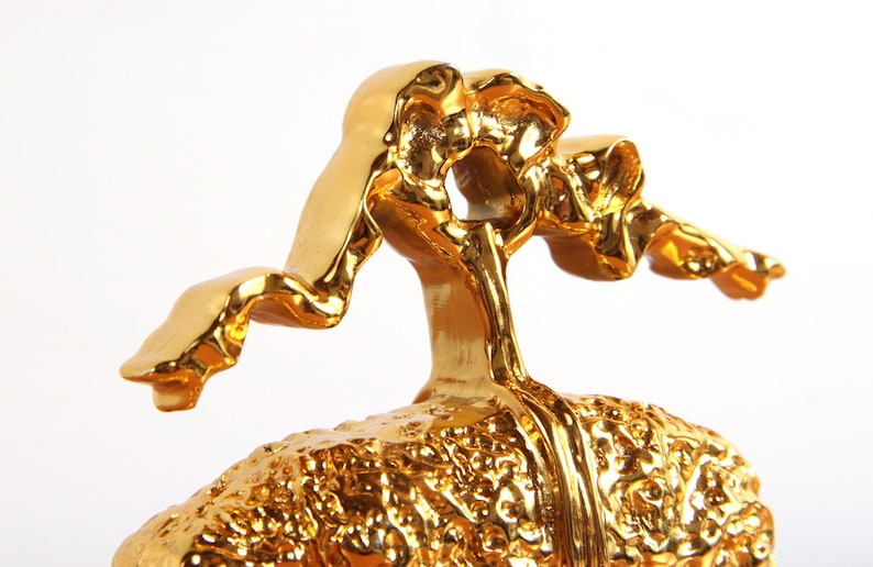 May include: A gold-colored ceramic sculpture of a human brain with a stylized, abstract figure on top.