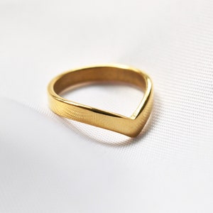 Könnte beinhalten: Ein goldfarbener Ring in V-Form.