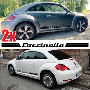 Puede incluir: Dos pegatinas de rayas laterales "Coccinelle" en blanco y negro para un coche. Las pegatinas se muestran en un Volkswagen Beetle gris y blanco. Las pegatinas están en el panel lateral inferior del coche.