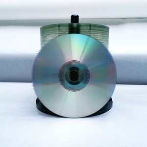 May include: A stack of blank silver CDs in a black plastic holder.