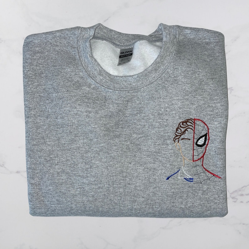 May include: Gray sweatshirt with an embroidered image of Spider-Man's face on the left side of the chest.