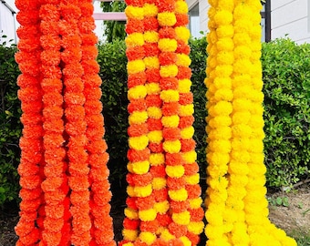 Könnte beinhalten: Drei Girlanden aus Ringelblumen in leuchtenden Farben: Orange, Gelb und eine Mischung aus Orange und Gelb. Die Girlanden sind dicht mit pomponartigen Blüten gefüllt und schaffen eine festliche und dekorative Präsentation. Ideal für Feiern und Veranstaltungen.