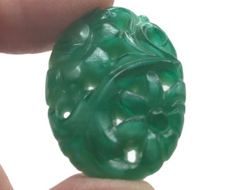 Puede incluir: Un colgante de jade verde tallado con un diseño floral. El colgante tiene forma ovalada y un acabado liso y pulido.
