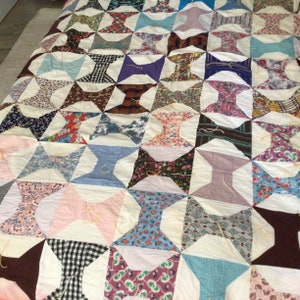 May include: A patchwork quilt with a white background and a variety of colorful fabrics in a bowtie pattern.