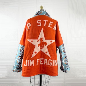 May include: Orange wool jacket with a large white star and the text "P STEK JIM FEAGIN" on the back. The sleeves are made of a blue and brown patterned fabric.