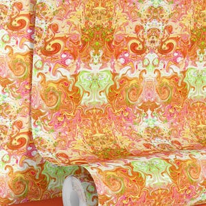 May include: A roll of wallpaper with a vibrant, abstract design. The pattern features swirling shapes in shades of orange, yellow, pink, and green, creating a dynamic and colourful visual effect. The wallpaper is partially unrolled, showcasing the repeating pattern.