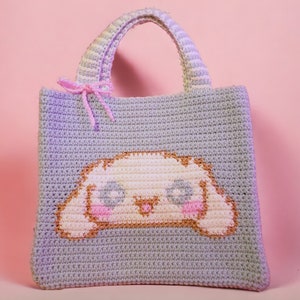 May include: A crocheted tote bag with a light gray background and a white cartoon dog face with pink cheeks and blue eyes.