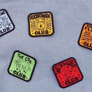 May include: Five embroidered patches with black borders and various designs. The patches include text such as "Bad Decisions Club," "Procrastinator Club," "Indoor Kids Club," "The CBA Club," and "Weird Girls Club."
