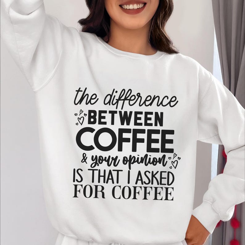 May include: White sweatshirt with black text that reads "the difference between coffee & your opinion is that I asked for coffee".