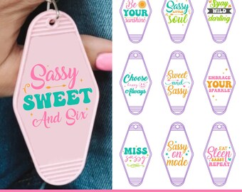 May include: A bundle of pink, purple, and white keychains with sassy quotes. One keychain reads "Sassy Sweet And Six". Other keychains have phrases like "Be Your Sunshine" and "Sassy Soul".