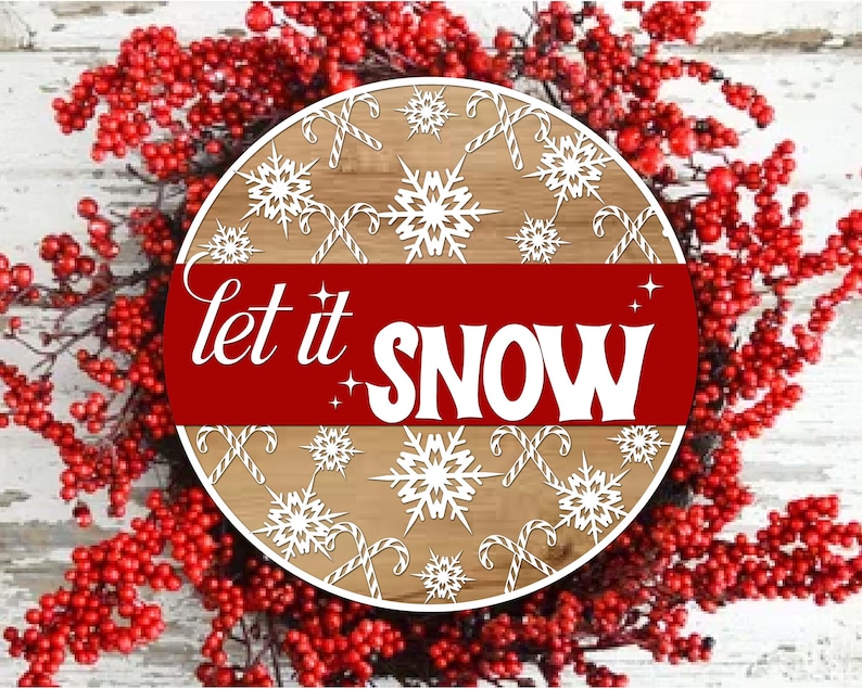 May include: A round wooden sign with the words "let it SNOW" in white on a red banner. The sign features snowflakes and candy canes on a light brown background, surrounded by a wreath of red berries.