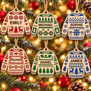 May include: Six laser-cut wooden sweater ornaments hanging by twine. Each ornament features a unique holiday pattern in red, green, or blue, with names Emily, Michael, Sophie, Olivia, Daniel, and James engraved in the center of each sweater.