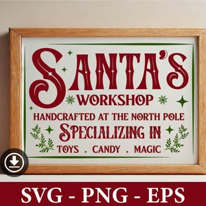 May include: A framed sign with a green border and red text that reads "Santa's Workshop* Handcrafted at the North Pole* Specializing in Toys. Candy. Magic".