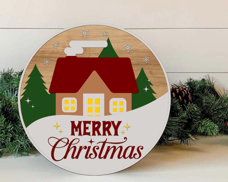 May include: A round Christmas decoration featuring a house with a red roof, green trees, and the words "MERRY Christmas" in a festive font. The design is set against a wood-grain background with a white border and star accents.
