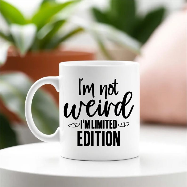 May include: White ceramic coffee mug with a black design that reads "I'm not weird I'm limited edition" with two small hearts on either side of the text.