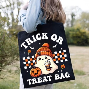 May include: Black canvas tote bag with the text "Trick or Treat Bag" in white retro font. A cartoon ghost wearing a knitted orange and brown hat holds a cup of coffee and is next to a jack-o-lantern.