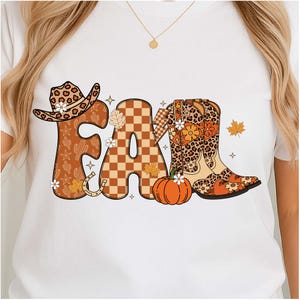 Könnte beinhalten: Weißes T-Shirt mit dem Wort "FALL" in einem herbstlichen Design. Die Buchstaben sind mit einem Cowboyhut, einem karierten "A" und einem Cowboy-Stiefel verziert. Das Design umfasst einen Kürbis, Blätter und florale Akzente.