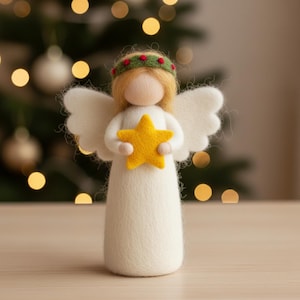May include: A handmade felt angel figure, holding a yellow star. The angel has white wings, blonde hair, and a green and red wreath. The figurine is a Christmas decoration, standing on a wooden surface.