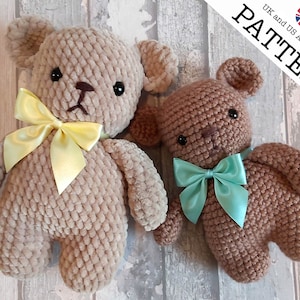 May include: Two crocheted teddy bears, one with a yellow bow and the other with a turquoise bow. The bears are brown and have black eyes. The bears are sitting on a wooden surface. UK and US Abbreviations PATTERN.