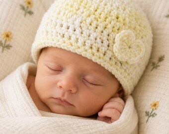 May include: A pale yellow and white crochet beanie featuring a small, matching crocheted flower accent on the side. The hat is constructed with a textured stitch pattern and has a simple, rounded shape that fits snugly around the head.