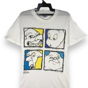 May include: White t-shirt with a graphic of four cartoon ghost faces in colorful squares. The text 