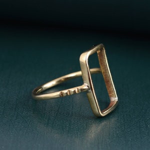May include: A gold-toned ring with a rectangular bezel setting. The ring is designed to hold a stone or other embellishment.
