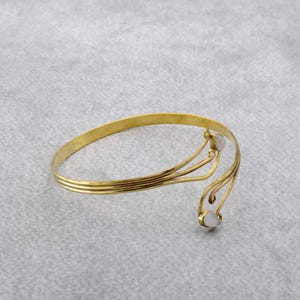 May include: A gold-toned bracelet with a delicate, curved design and two white stones.