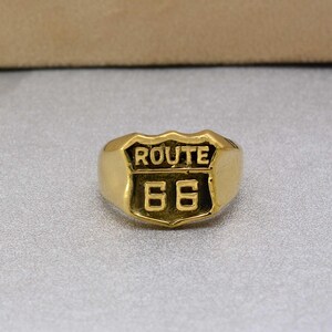 May include: Gold-colored ring with a raised Route 66 sign design.