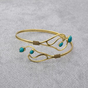 May include: A gold-toned bangle bracelet with a delicate, twisted design and turquoise gemstones.