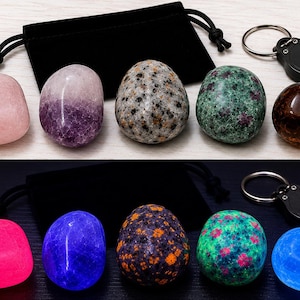 May include: A set of five polished stones including a pale pink quartz, a purple amethyst, a speckled granite egg, a green and red zoisite, and a dark amber stone, accompanied by a black velvet drawstring pouch and a small UV keychain light.