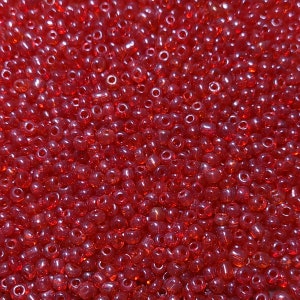 May include: A close-up image of a large quantity of small, round, red glass beads. The beads are translucent and have a slight shimmer.