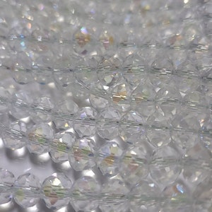 May include: A strand of clear iridescent glass beads. The beads are faceted and have a round shape.