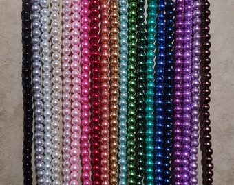 May include: A collection of beaded strands in a variety of colors, including black, silver, white, pink, red, gold, green, blue, purple, and brown. The beads are uniform in size and appear to be pearls, creating a visually appealing display.